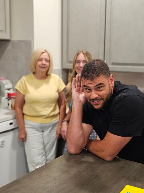 Untitled Shane Shannon leaning on a kitchen counter with Kathy Archer and Sarah Jobin Spaller behind him.